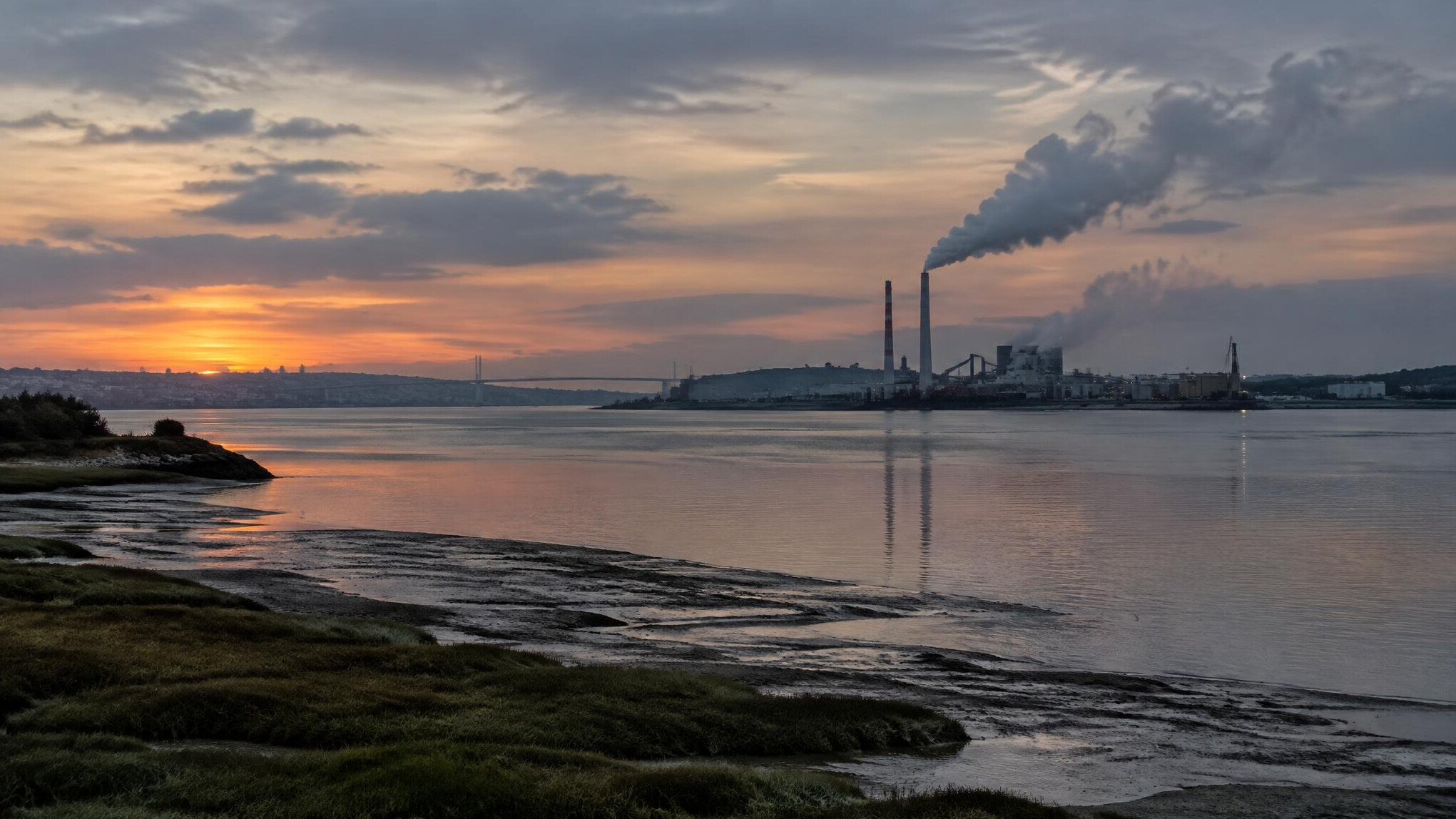 Rio português com fumo industrial ao fundo